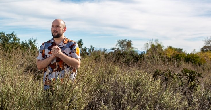 Arthur Levin stands with hands clasped in the foliage of the Bernard Field Station