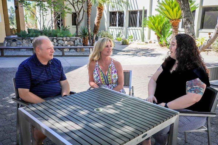 Jim, Kelly, and Tracy sit at a table in Scott courtyard