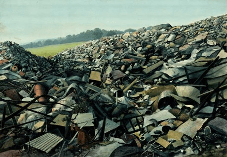 up-close view of a mountain of trash with green grass and trees in the distance.