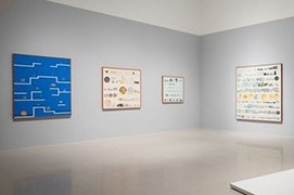 a gallery with grey walls and four paintings on them