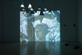 head of a classical statue projected onto a wall in a dark room