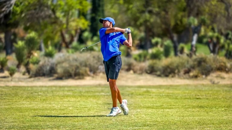 A member of the Pomona-Pitzer men's golf team swings a club on a green field.