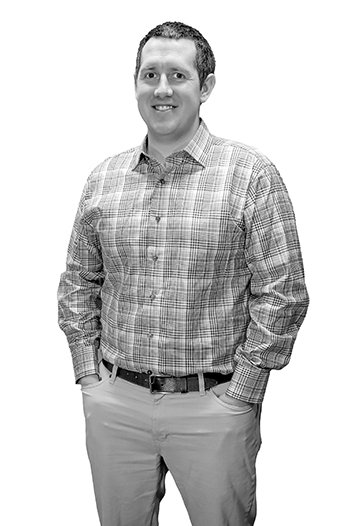black and white portrait of a man in a plaid shirt and chino pants