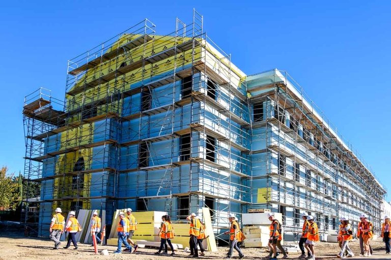 people in hard hats and visibility vests tours the outside of the nuclues during construction