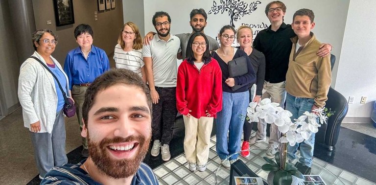 a group of students and professors pose as a group in the president's office waiting room