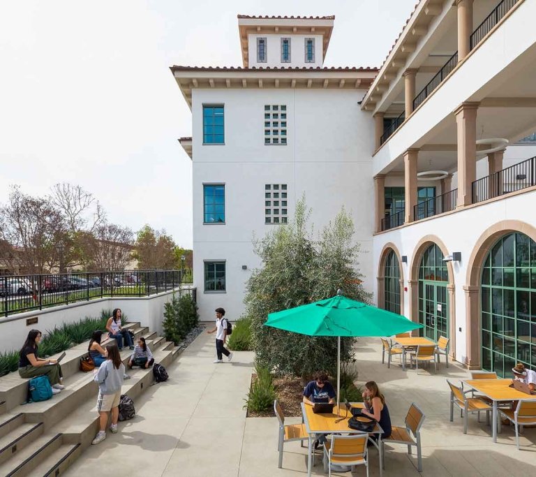 students gather in an outdoor patio area to work and socialize