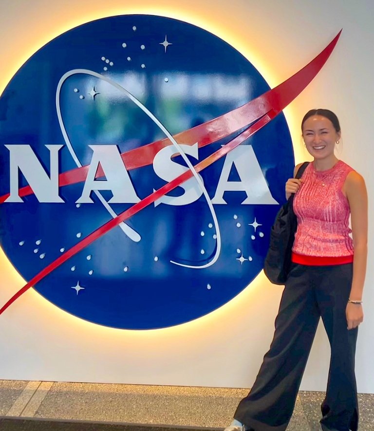 Scotia Rollins stands in front of a NASA logo