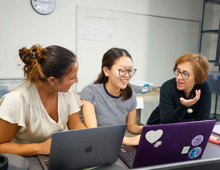 two students meet with a faculty member in a nucleus classroom