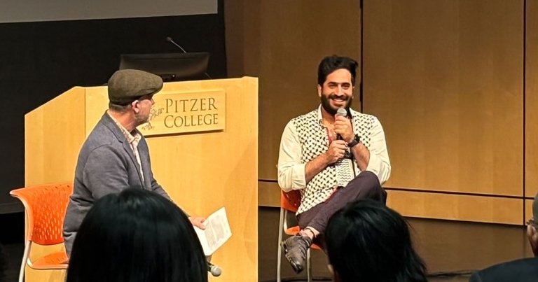 Poet Yahya Ashour sits on Benson Auditorium's stage with professor Brent Armendinger