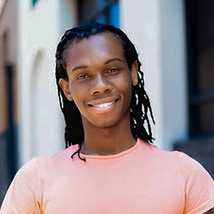 Close-up of Jonah Konah wearing a pale orange T-shirt and with medium-length black hair.