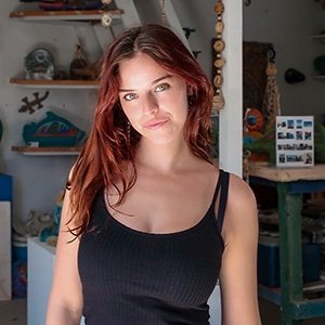 Close-up of May Paterniti wearing a black tank top and with long wavy red hair.