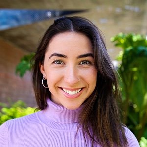 Close-up of Sadie Scott wearing a lilac turtleneck and with long wavy dark hair.