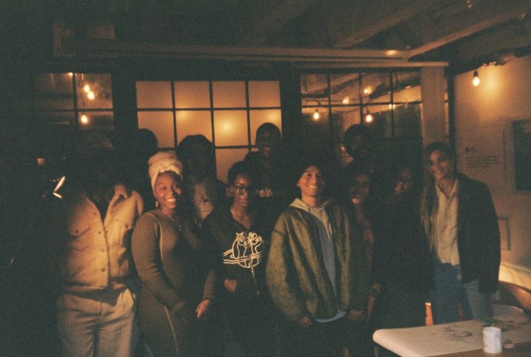 A dozen students stand together and smile in Memoryhaus 555.