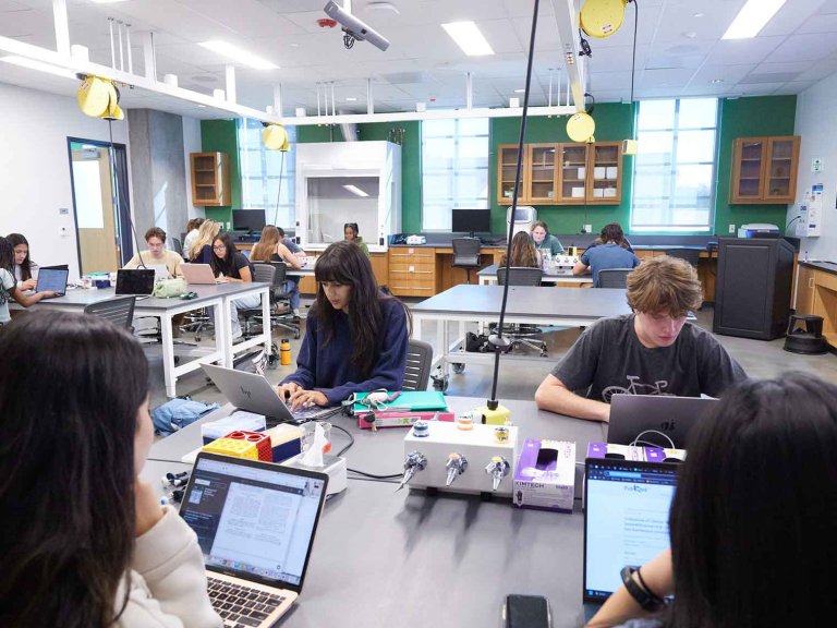 four students sit at a collaborative table in a biology lab