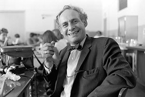 arthur dubinksy wears a bow tie and blazer while stting in a large room