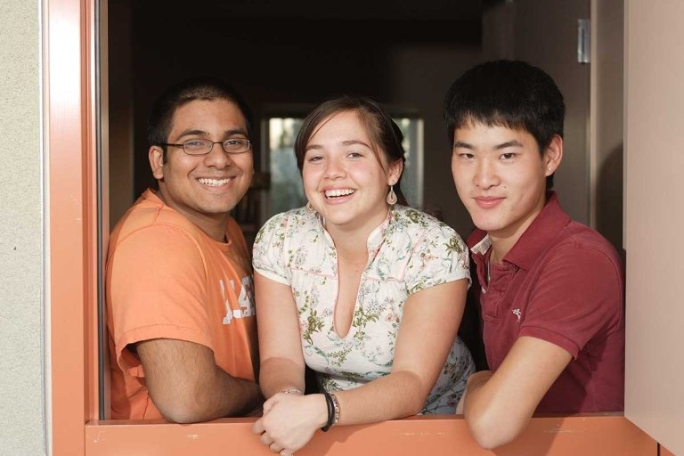 three students stand behind an open dutch door in a dorm room in PAS Hall