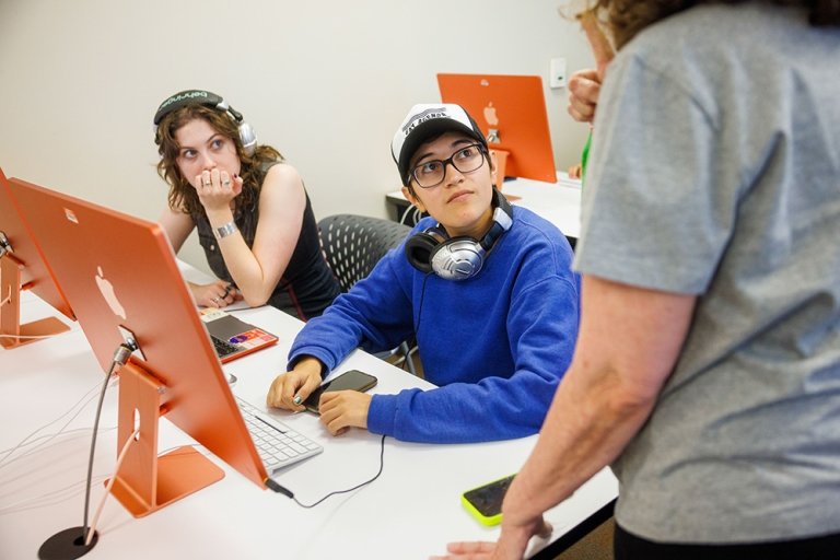 Two students talk with a friend in the Pitzer computer lab