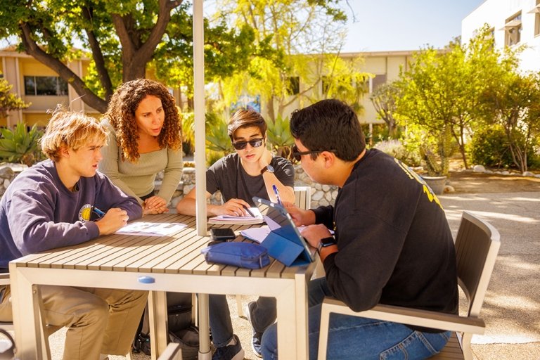 Pitzer students review assignments with a professor outside the Pit Stop Cafe