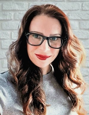 Nydia Armendia-Sanchez has long wavy dark hair and wears black-rimmed glasses and a gray sweater.