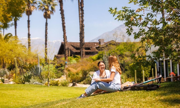 two students sit on the mounds with a laptop