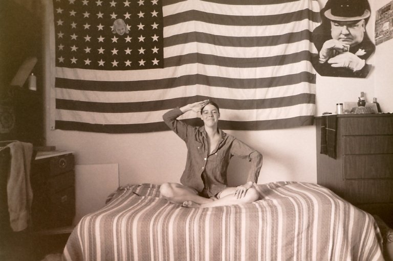 A 1960s photo of a Pitzer student saluting in her dorm room