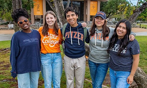 five students wearing pitzer shirts pose in front of McConnell apron
