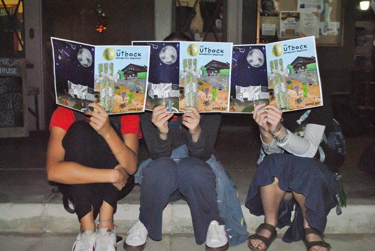Students show off print issues of The Outback at a release party