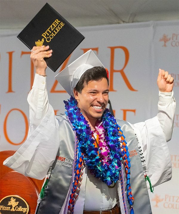 A Pitzer student holds his diploma aloft during Commencement