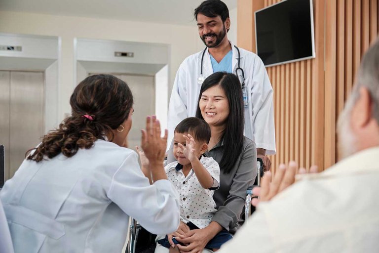 a student intern interacts with a mother and child while a doctor looks on