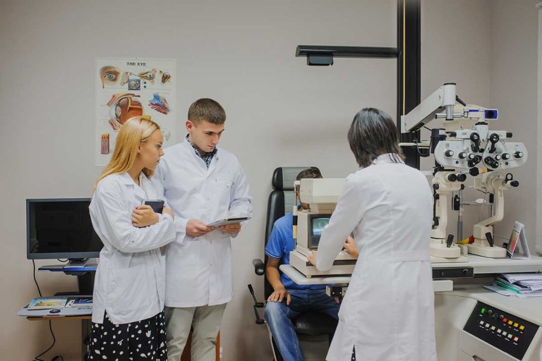 two students shadow an optometrist while she gives a ocular test