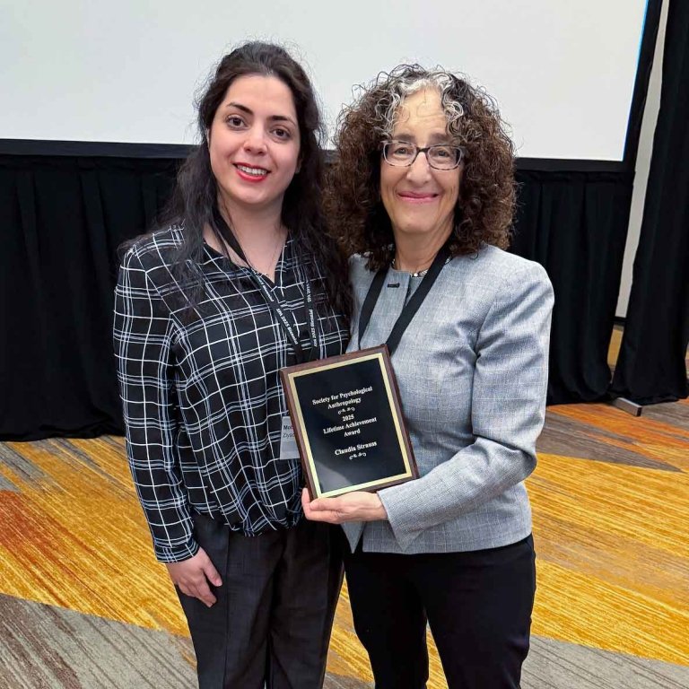 a woman holds up an award in an auditorium