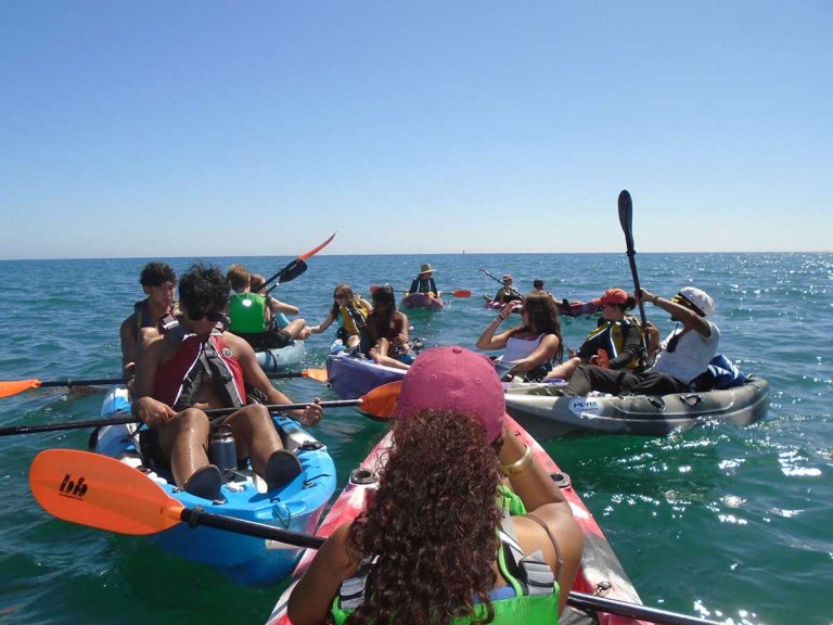 several students kayak in the ocean on an orientation adventure