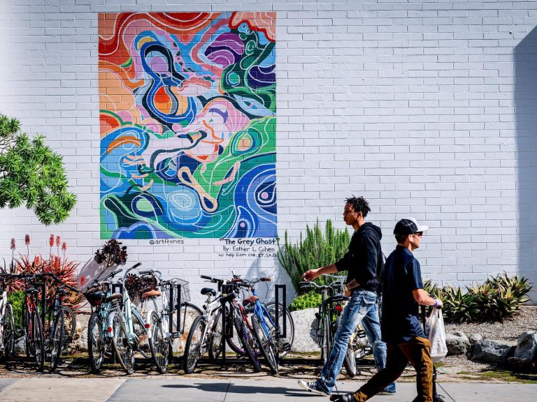 two student walk past a colorful abstract mural