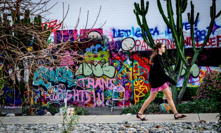 a student walks past a heavily graffitied wall.
