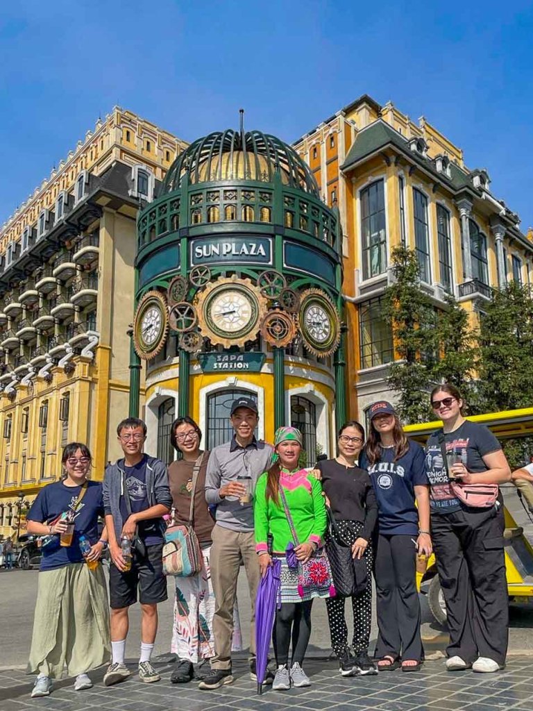 a group stands in front of the sun plaza clock