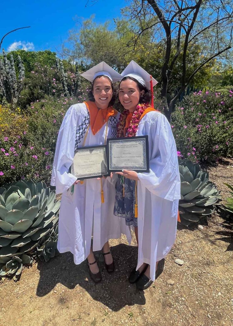 two students pose with their diplomas