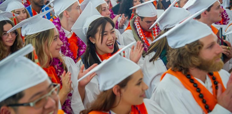 students in graduation gowns and hats cheer