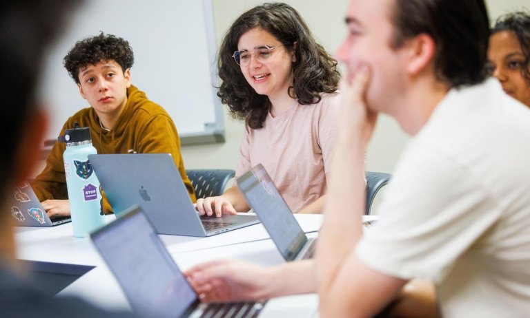 students discuss at desks in a classroom