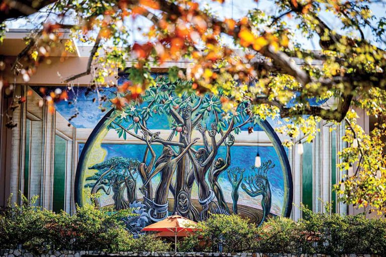a brown and bright blue mural depicting tree figures with human forms