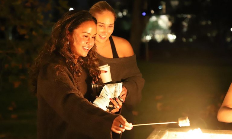 two students roast marshmallows during a family weekend event