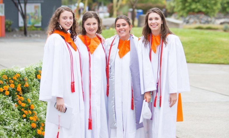 four students pose in their graduation regalia