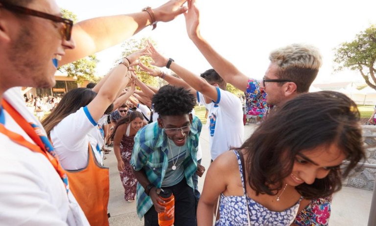 new students walk under an arm bridge