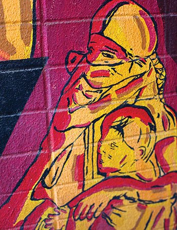 a mural of a masked woman cradling a child
