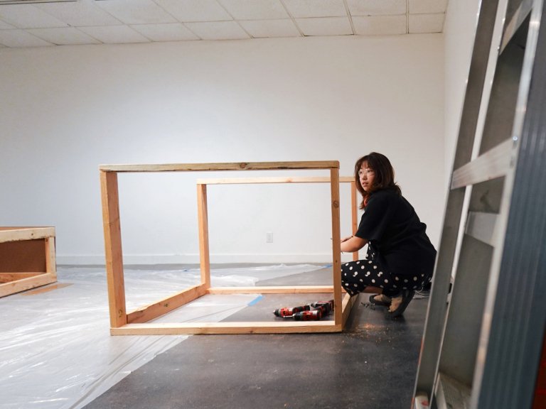 Female artist constructs box out of wood pieces