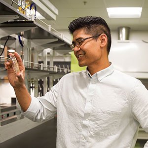 Pete Chandrangsu holds up a beaker in a science lab