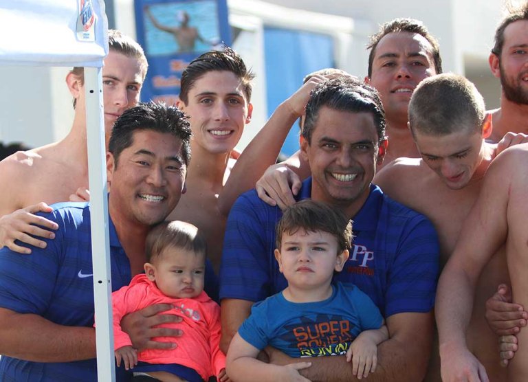 two coaches pose with students at a swim meet