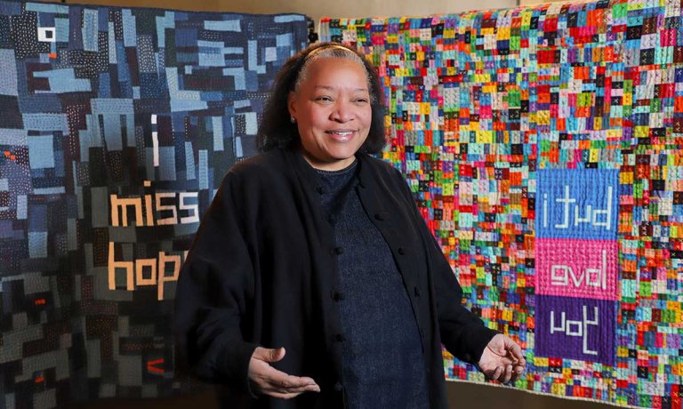 Chawne Kimber stands in front of two of her quilts