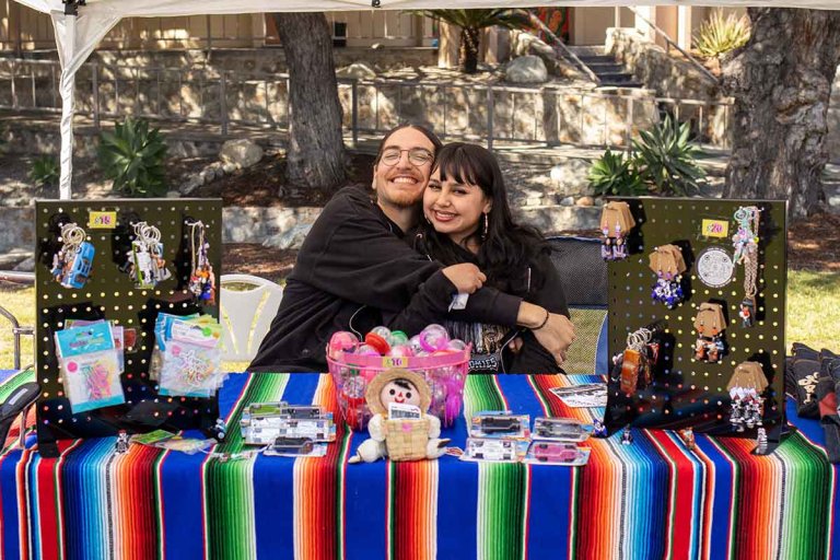 two people sit behind a vendor table on the Mounds