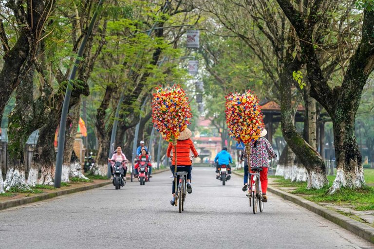 people ride bikes and motobikes on a street in Hue Vietnam