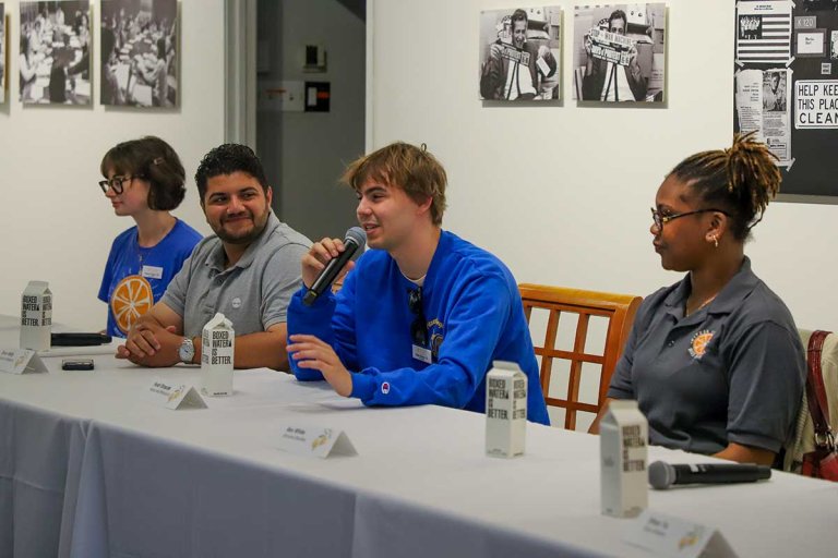 Noah Straus sitting at a table speaking into a microphone